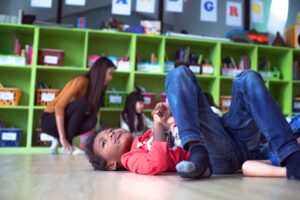 Young boy laying down on the floor in his classroom 