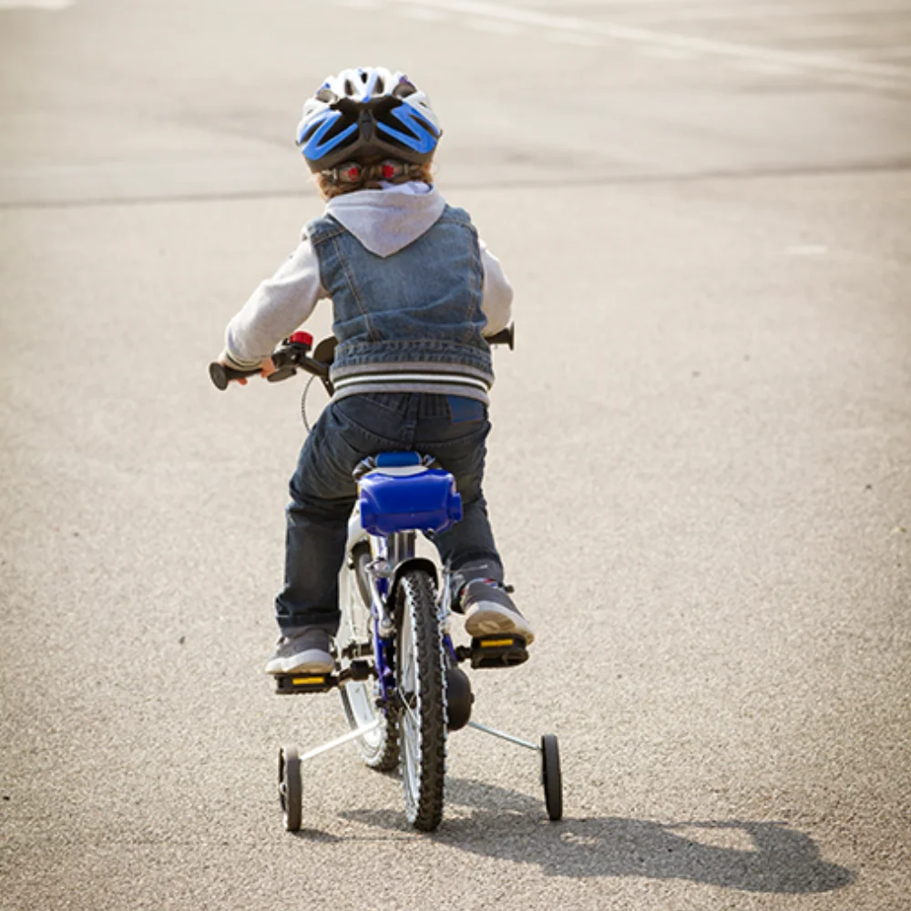 Energizing and Calming Activities for Expanding Communication Child riding bicycle with training wheels.