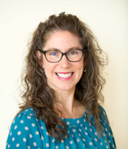 Headshot of Anne Overcash, a woman in a teal shirt and glasses